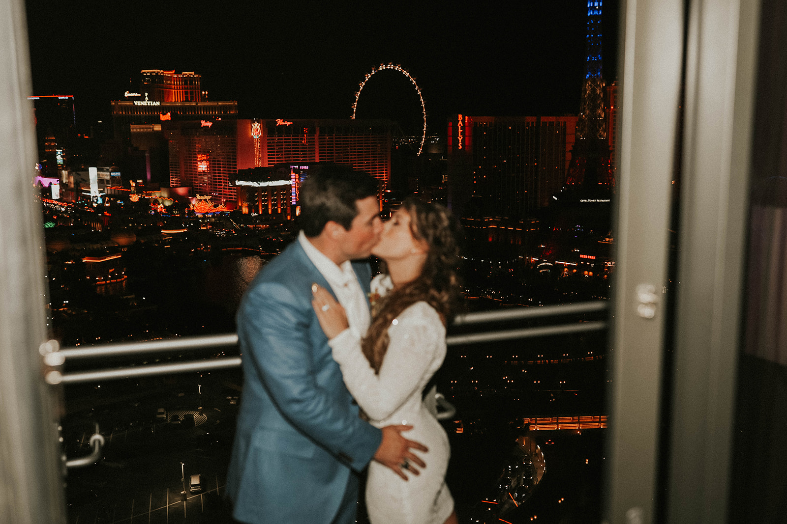 Couple Kissing on Balcony at The Cosmopolitan of Las Vegas with High Roller in Background 