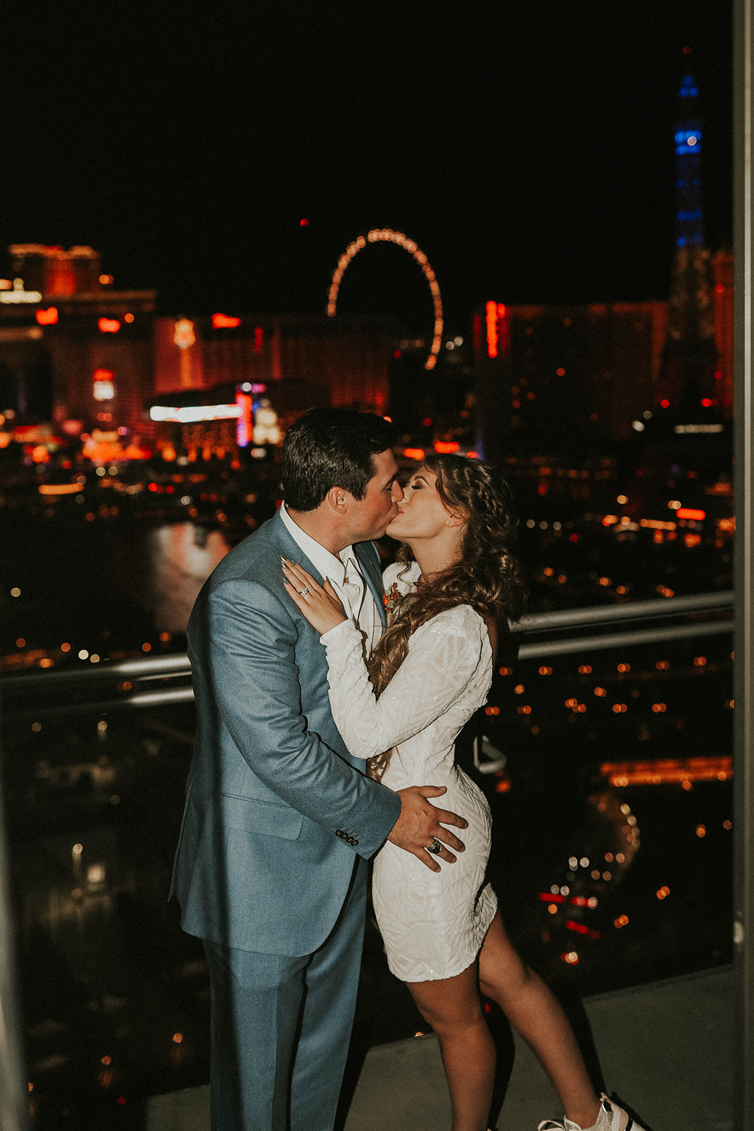 Couple Kissing on Balcony at The Cosmopolitan of Las Vegas with High Roller in Background after Bride Changed into Second Dress for Las Vegas Strip After Party 