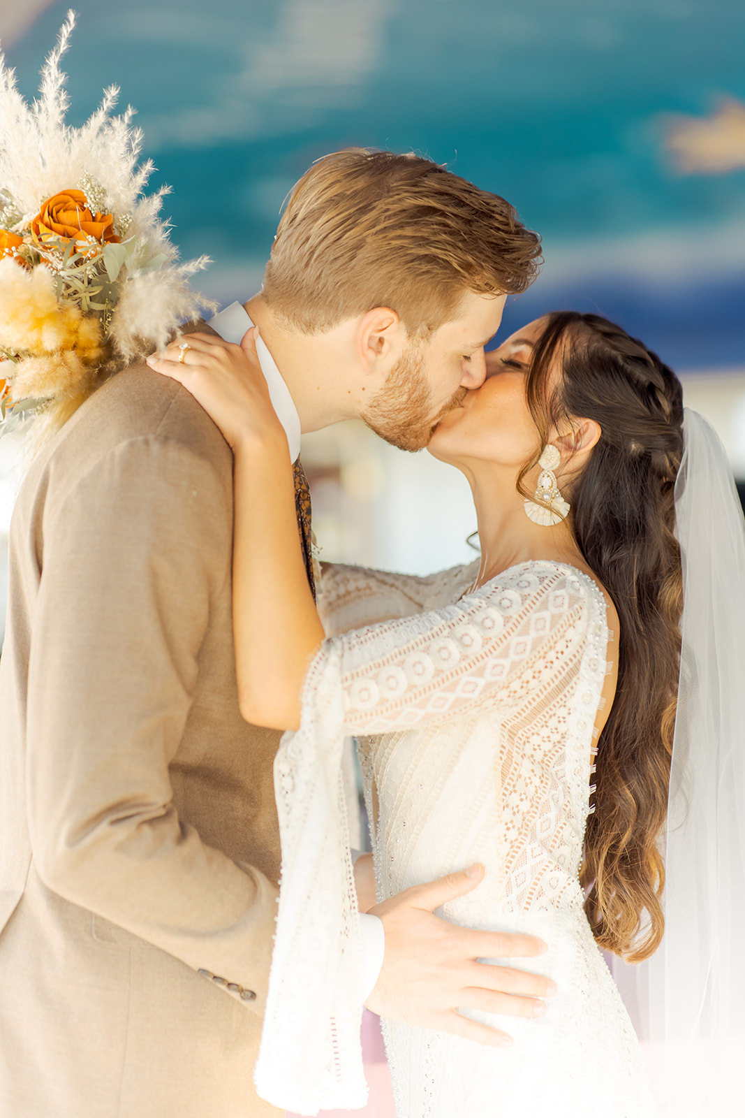 Bride in Detailed Boho Lace Dress Kissing Groom after Ceremony 