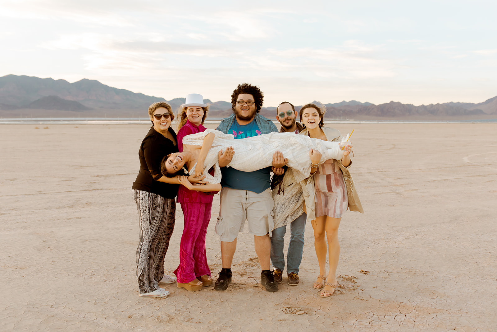 Guests holding bride on Dry Lake Bed during 70's wedding 