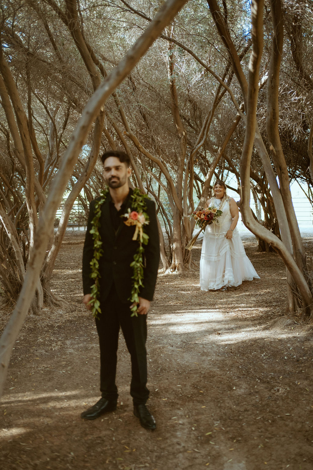 Groom in All Black Suite & Wedding Lei waiting for First look in Olive Grove at GreenGale Farms in Las Vegas 