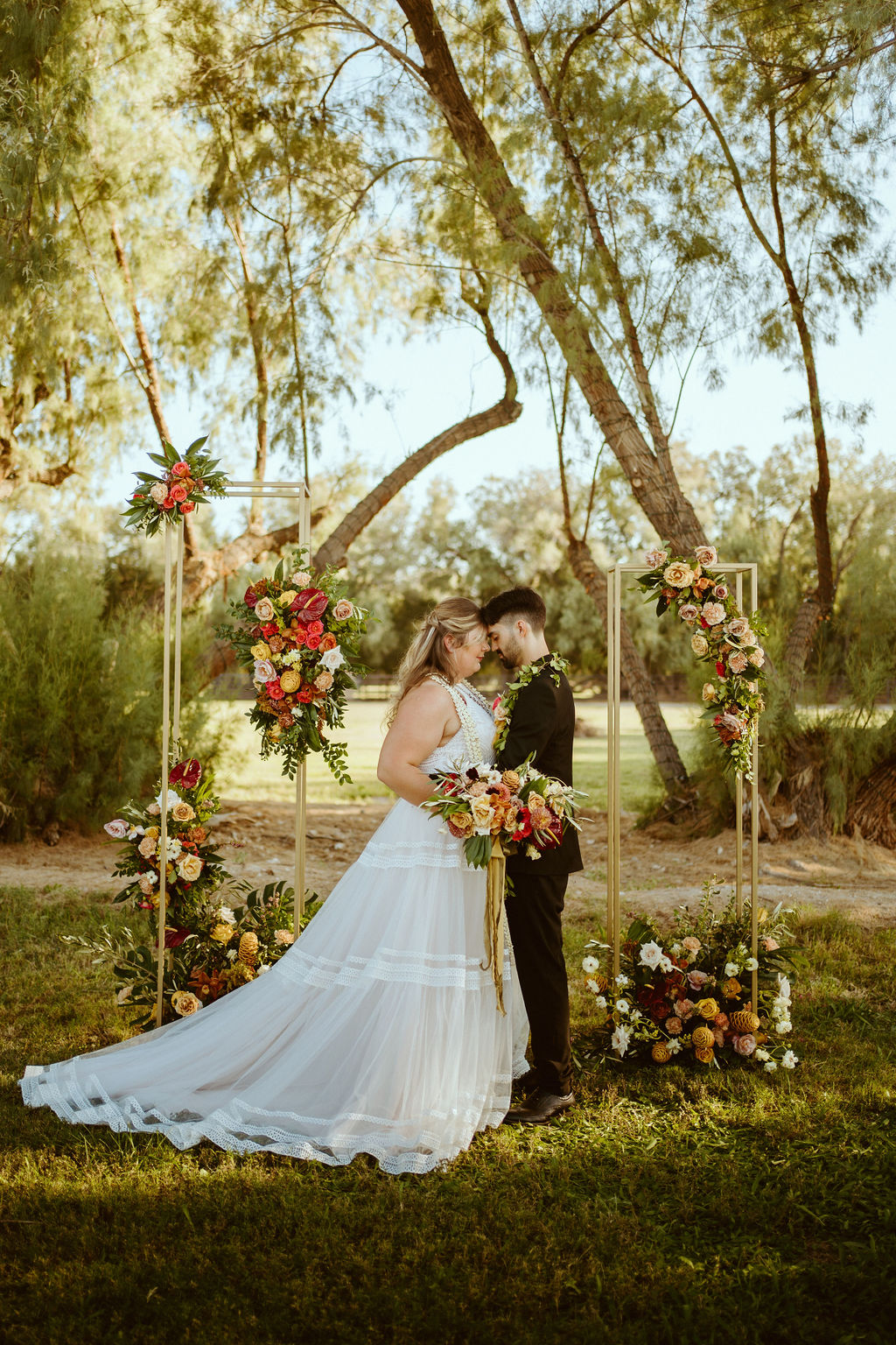 Newlyweds Standing Forehead to Forehead with Hawaiian Inspired Bouquet, Leis, and Gold Stand Altar after GreenGale Farms Hawaiian Elopement in Las Vegas 
