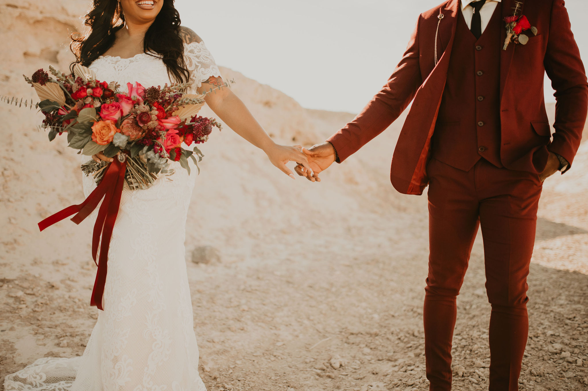 Bride Smiling with Bouquet Holding Hands with Groom in Burgundy Suit Jewel Tone Las Vegas Elopement 