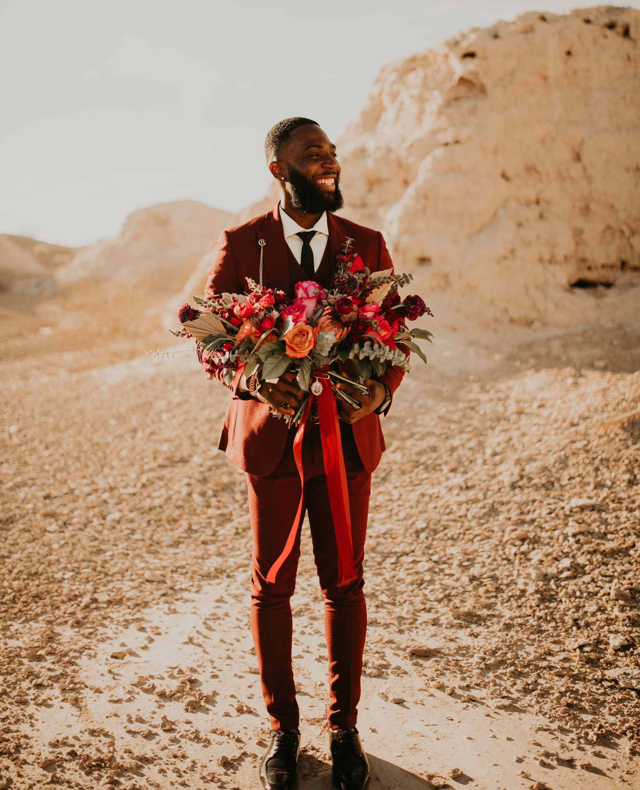 Groom in Burgundy Suit holding Brides Jewel Tone Bouquet with Bridal Pendant 