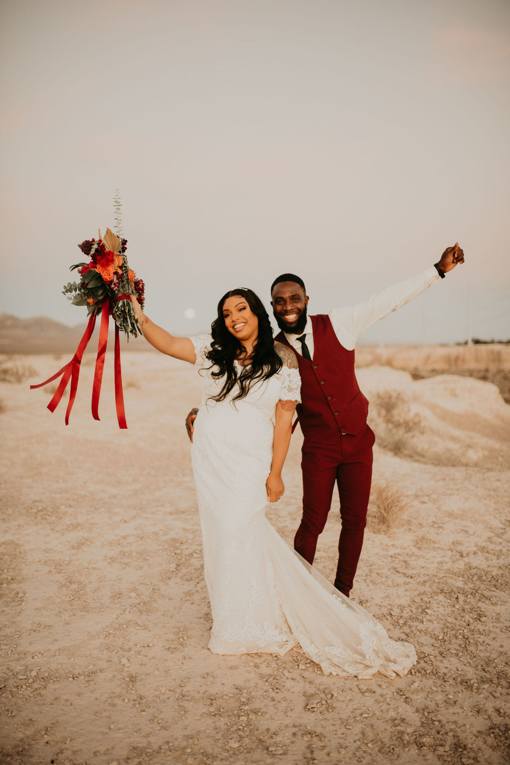 Couple Celebrating with Hands up in Jewel Tone Las Vegas Elopement with Full Moon behind them 