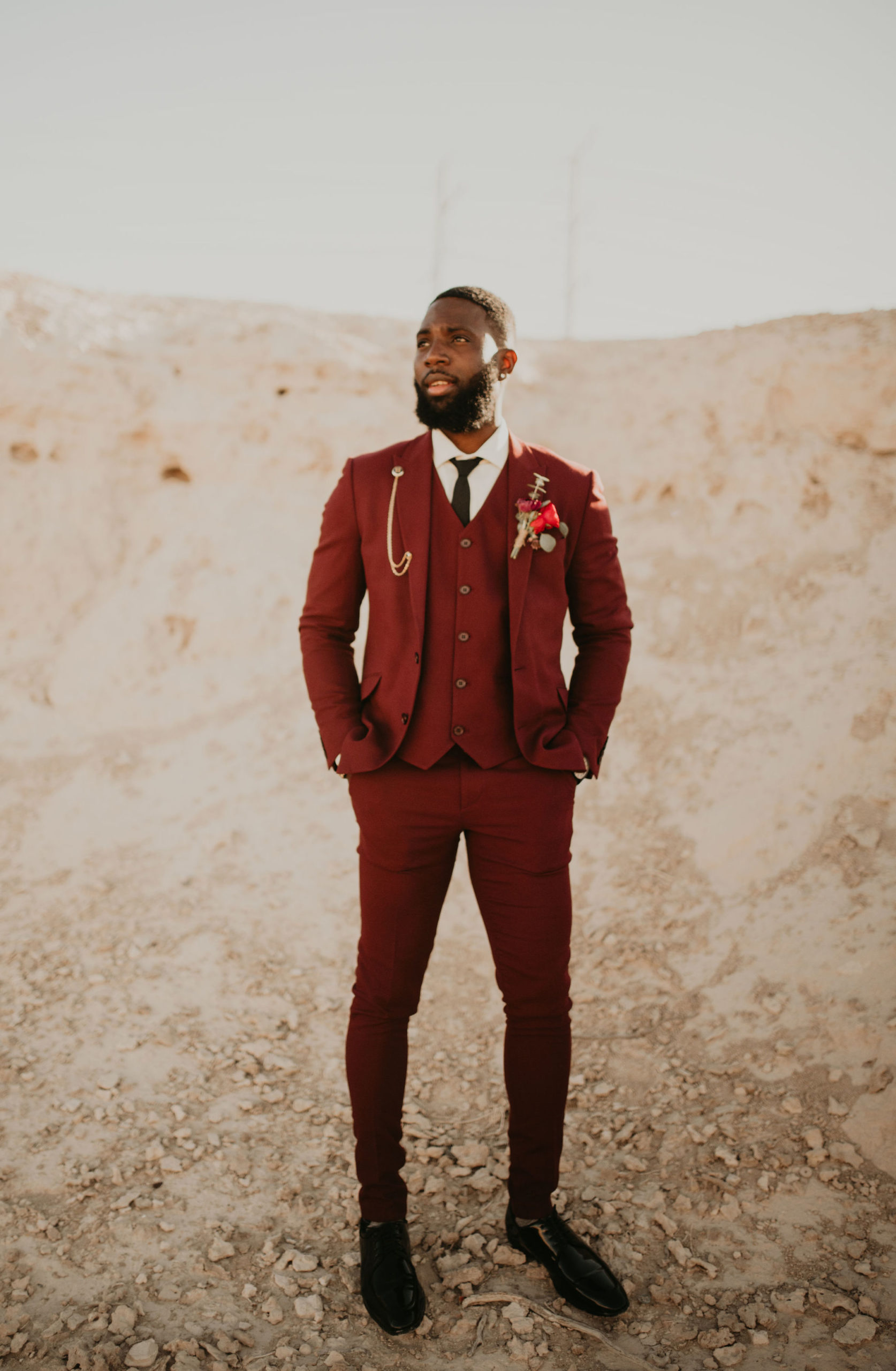 Groom in Burgundy Suit with Boutonnière Prepping for First Look in Las Vegas Desert 