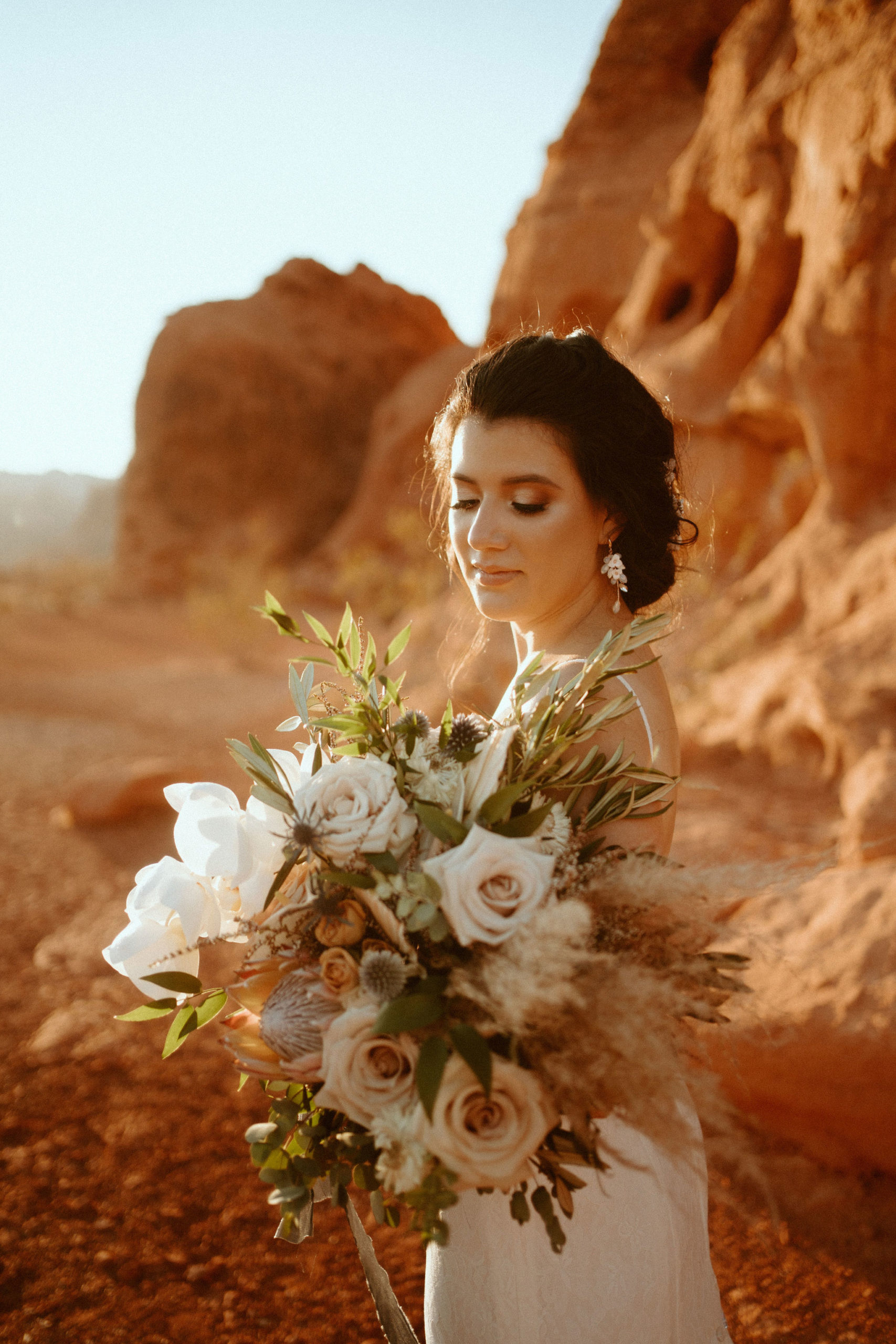 Bride Looking Down at Modern Boho Bouquet and Showing Bridal Make-up 