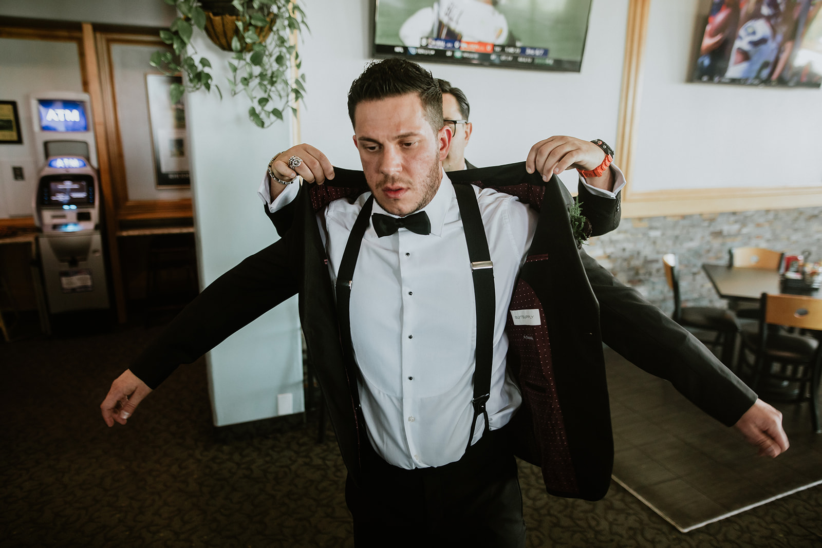 Groom with bow-tie putting on Jacket before getting married 