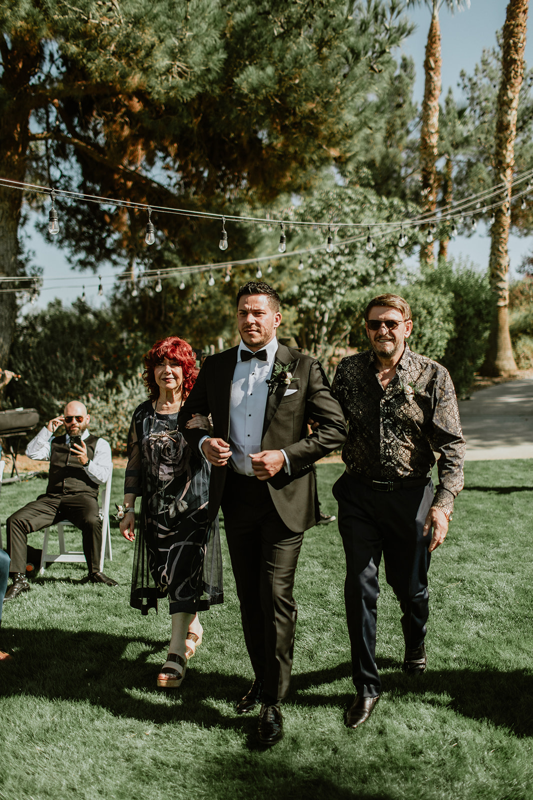 Groom walking down aisle with parents 