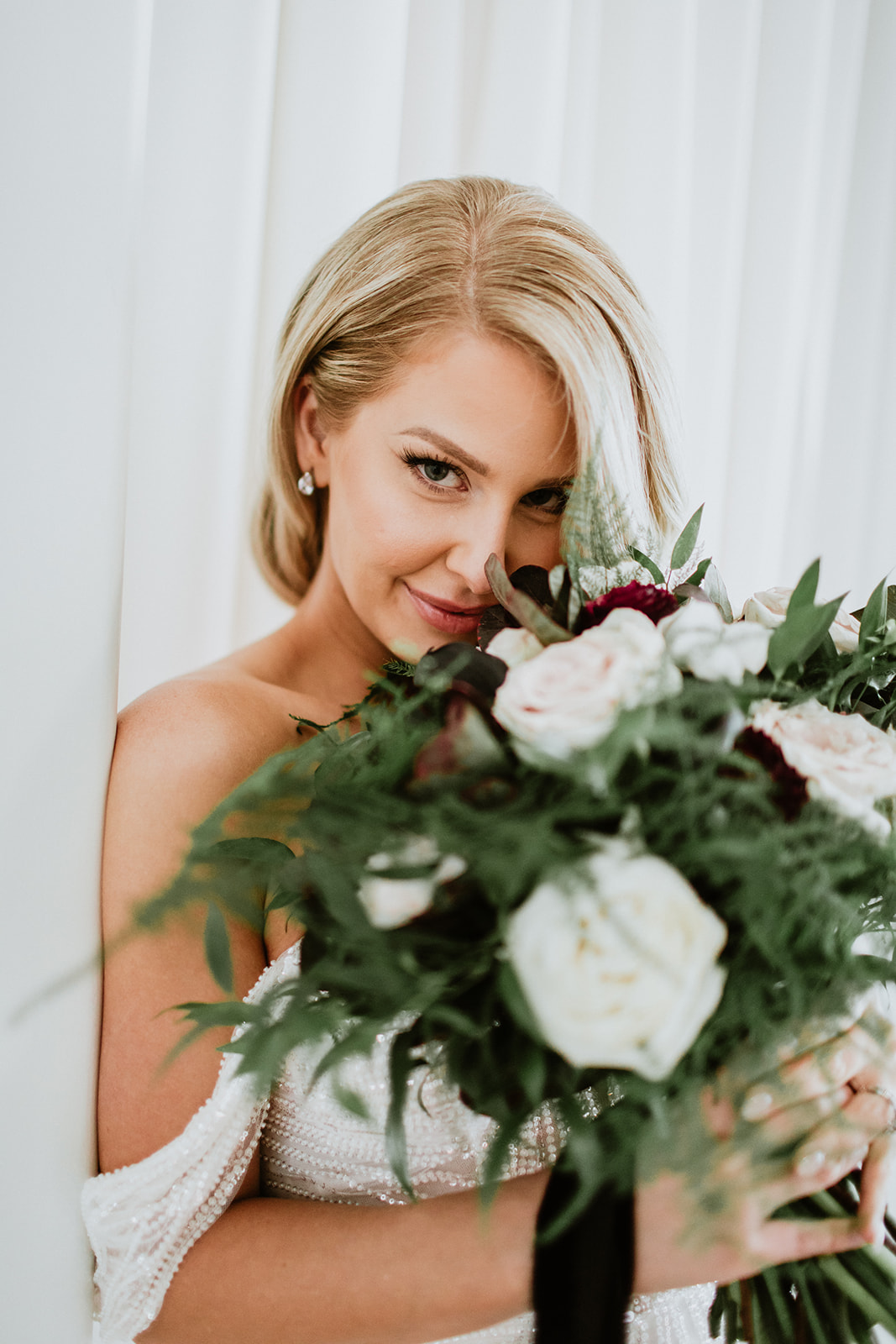 Bride smiling with round bouquet with greenery 