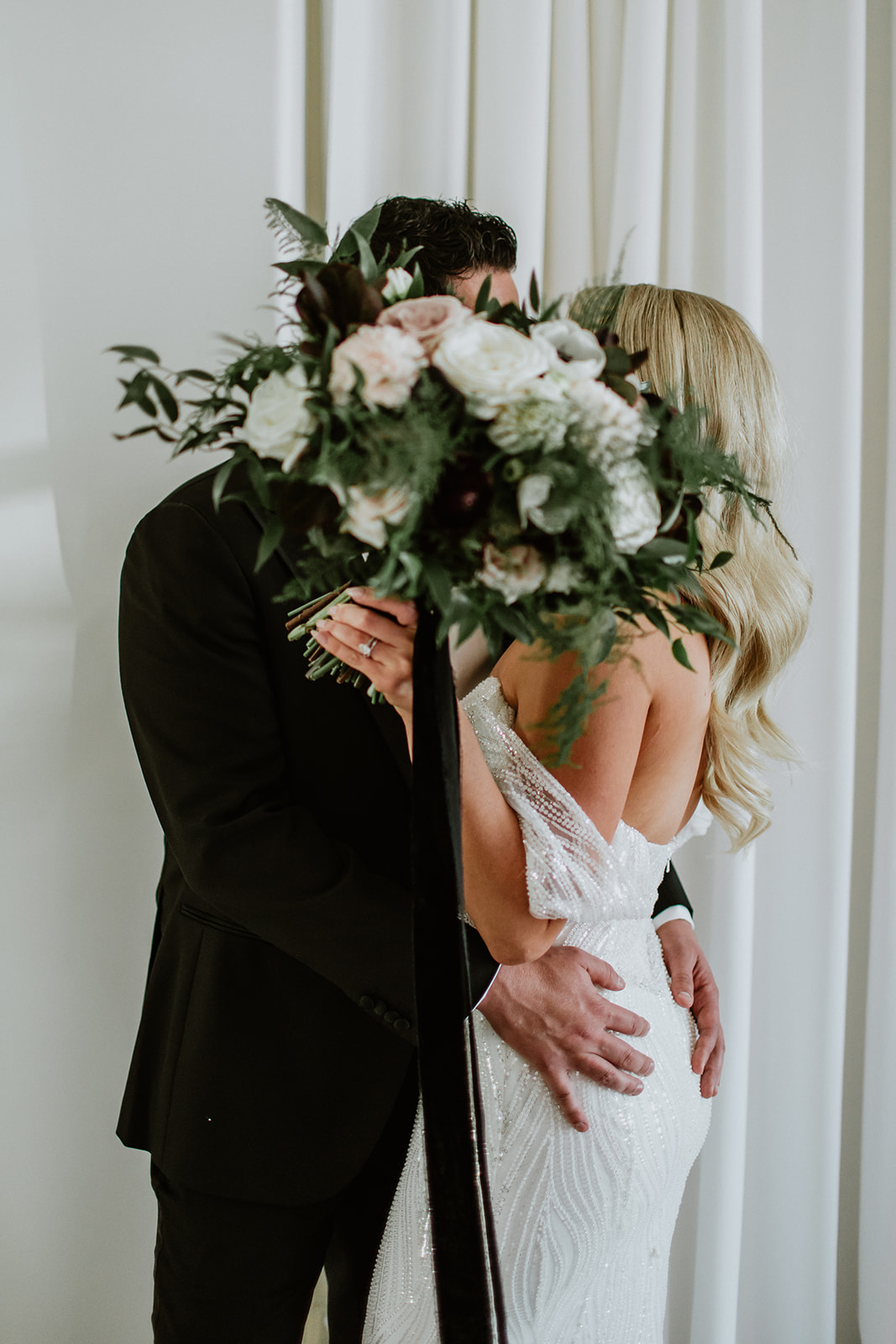Newlyweds kissing behind bouquet 