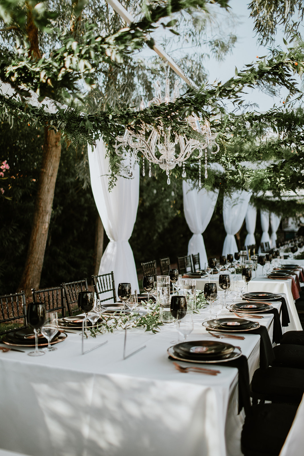Moody Modern Glam Lotus House Wedding Reception tablescape with chandelier and greenery overhead 
