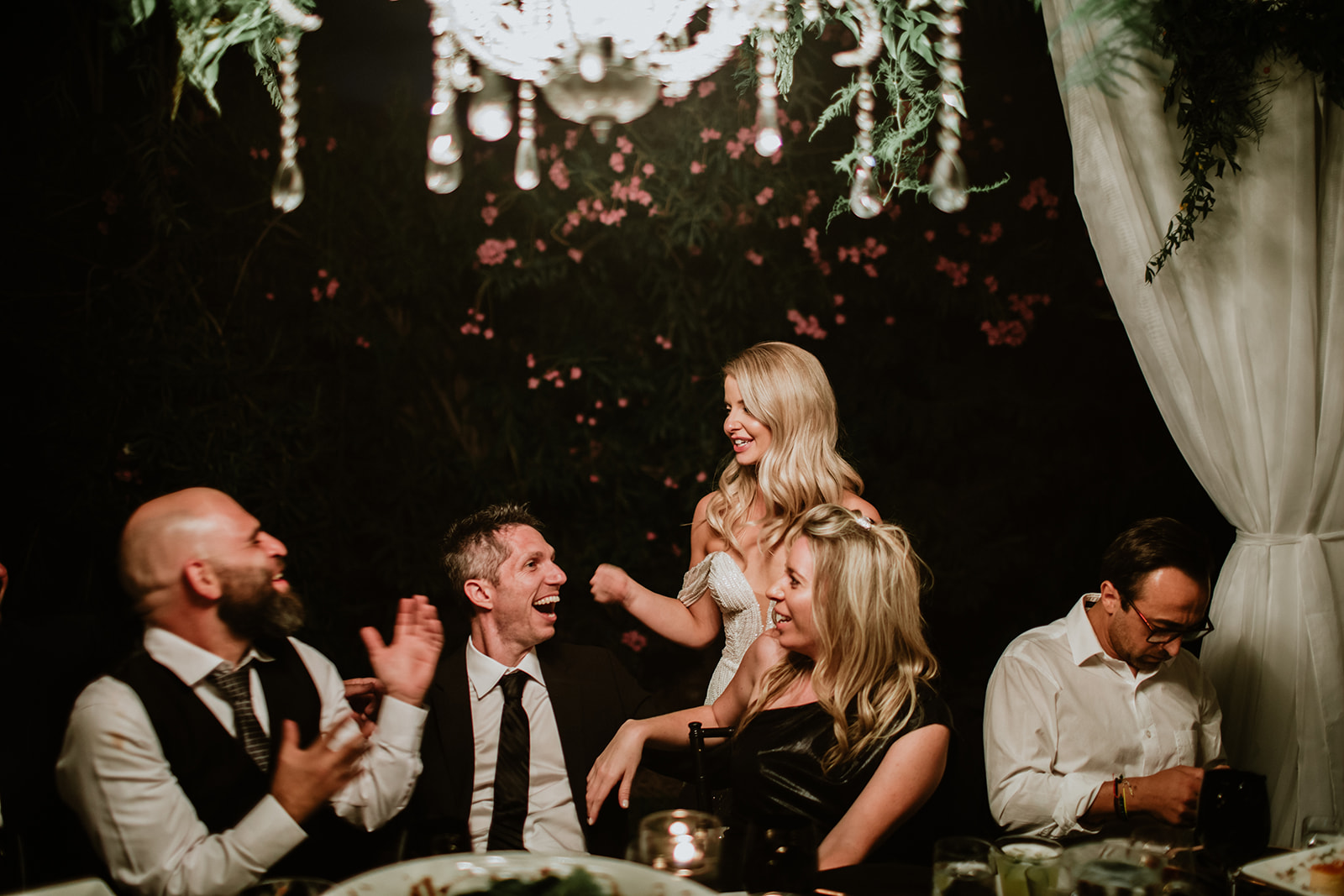Bride laughing with guests during dinner reception 