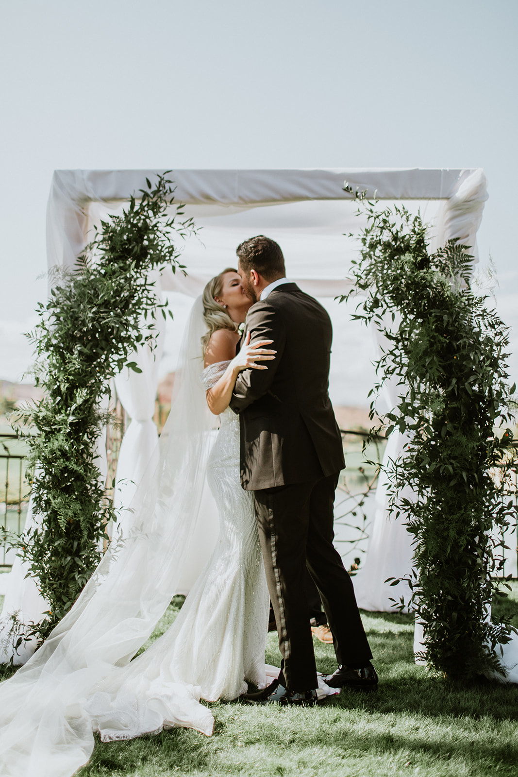 Newlyweds First Kiss under Chuppah with Greenery 
