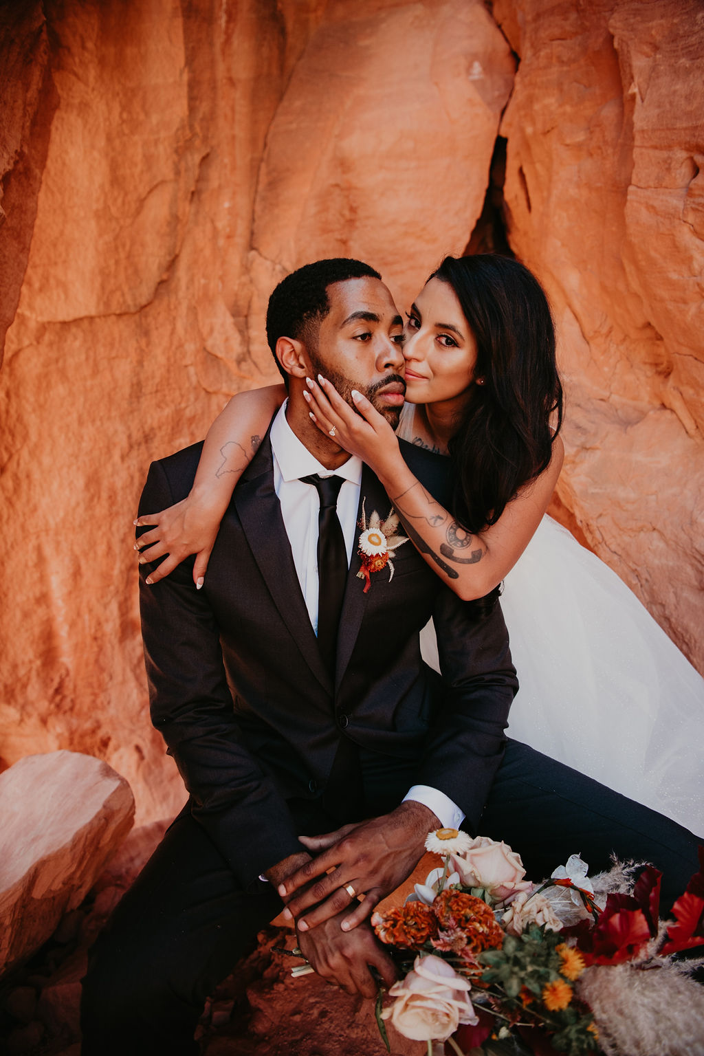 Bride and Grooms Embrace while Groom is Sitting and Holding Bouquet in Las Vegas 