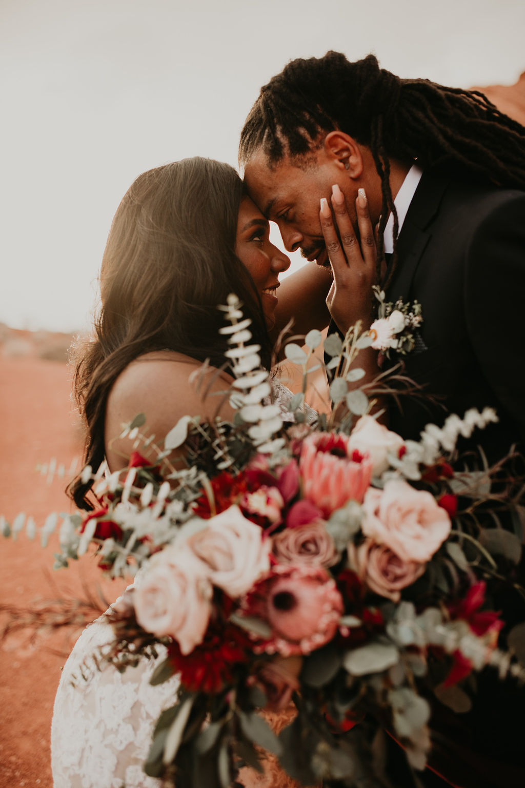 Couple Forehead to Forehead with Bouquet in Rustic Pink Burgundy and Sage Elopement 