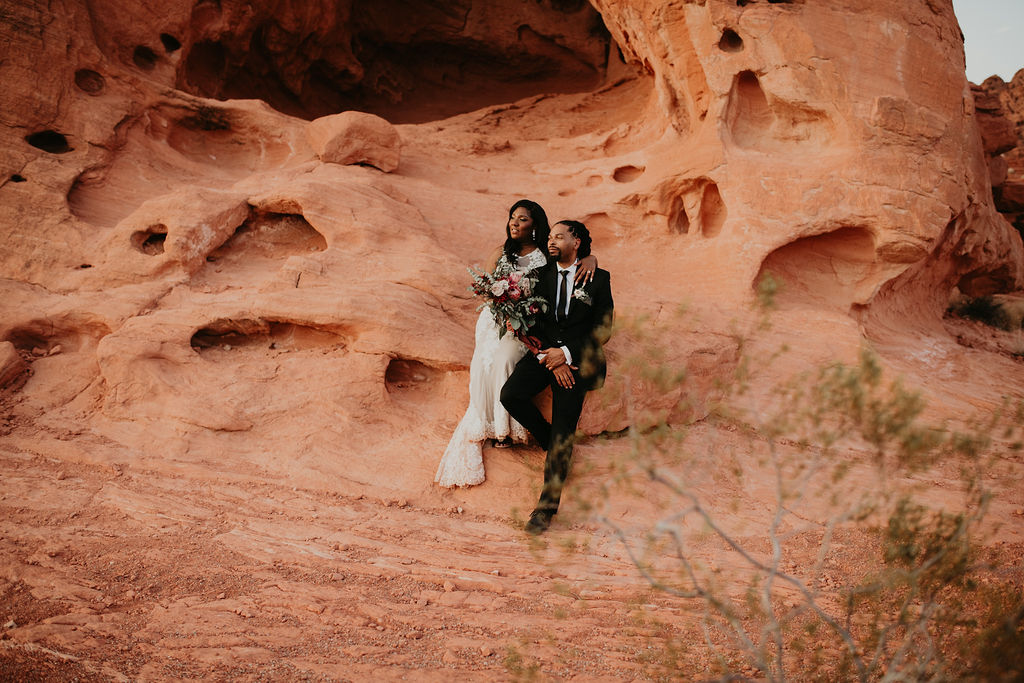 Bride and Groom sitting on Dramatic Valley of Fire Rocks for Rustic Pink Burgundy and Sage Elopement 