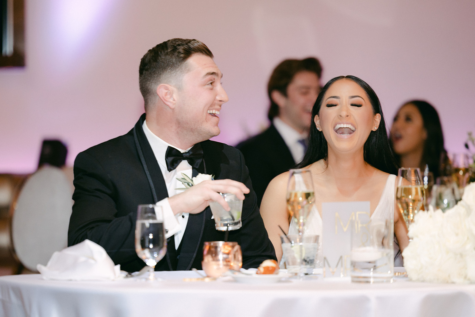 Bride and groom laughing at sweetheart table 