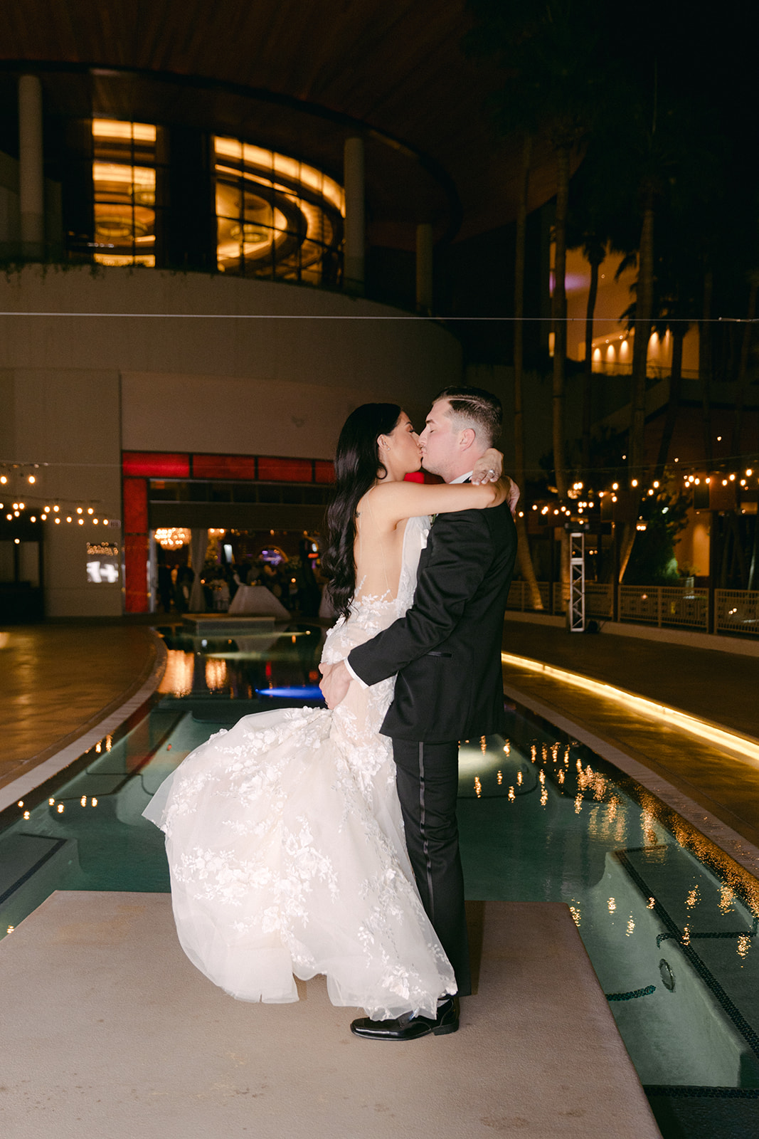 Bride and groom kissing in front of Red Rock Casino pool during wedding 