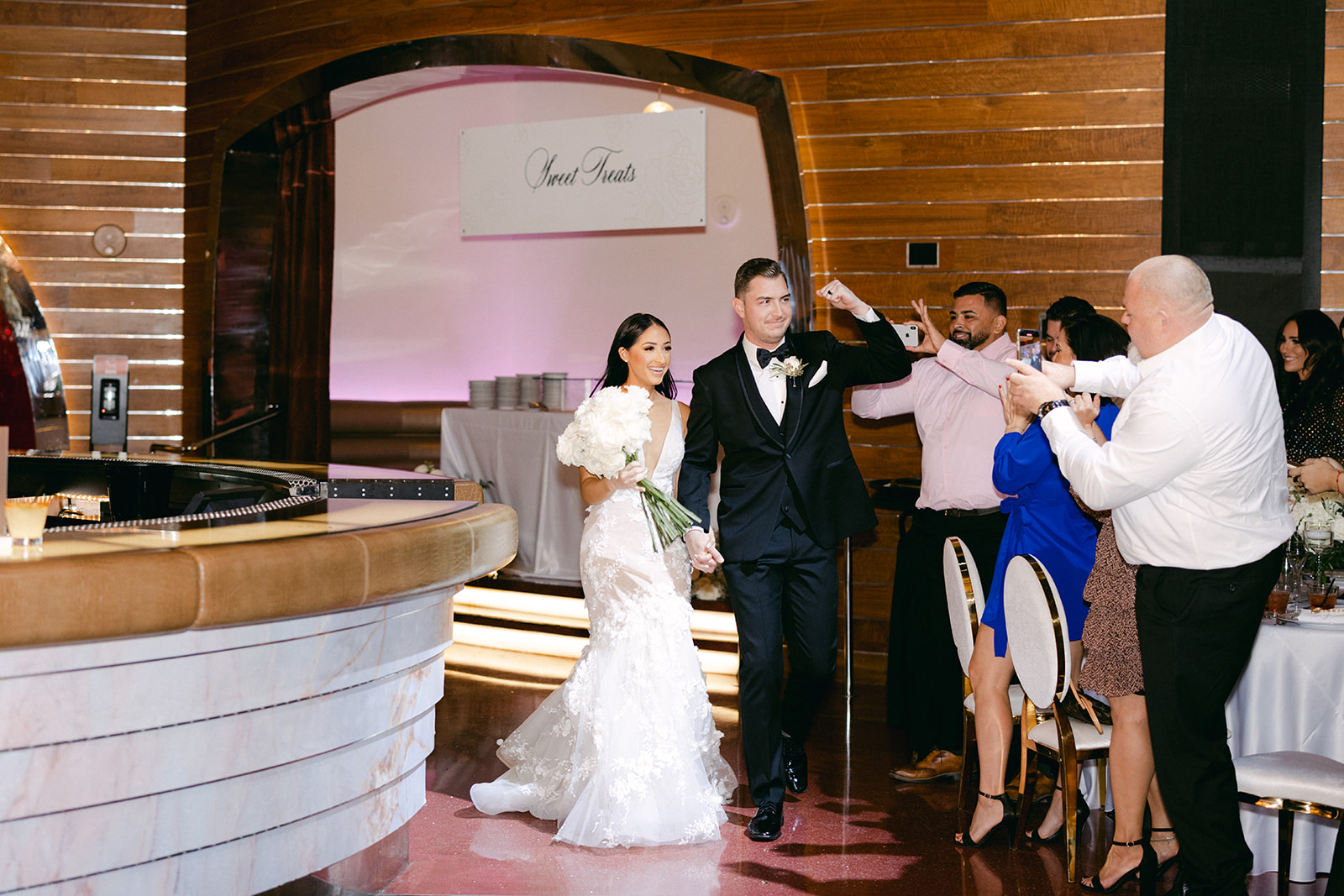 Couple making grand entrance into the reception as guests celebrate 