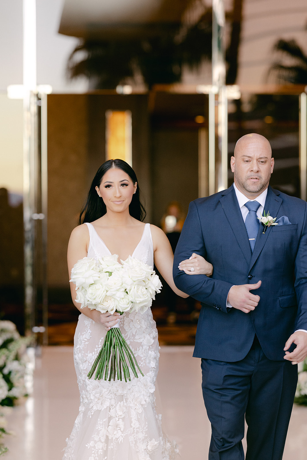 Bride with white rose bouquet walking down aisle with father 