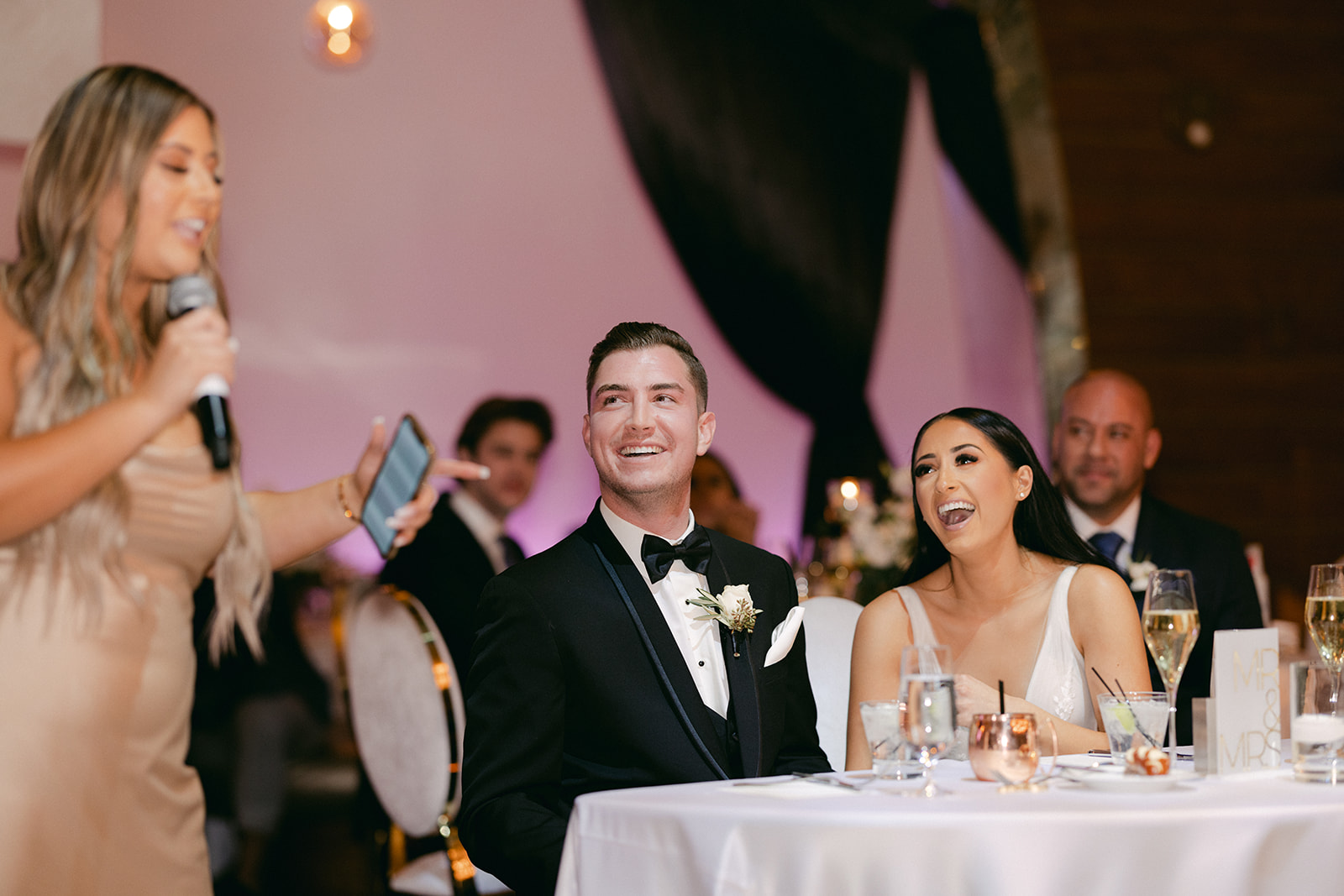 Newlyweds laughing during bridesmaids speech 