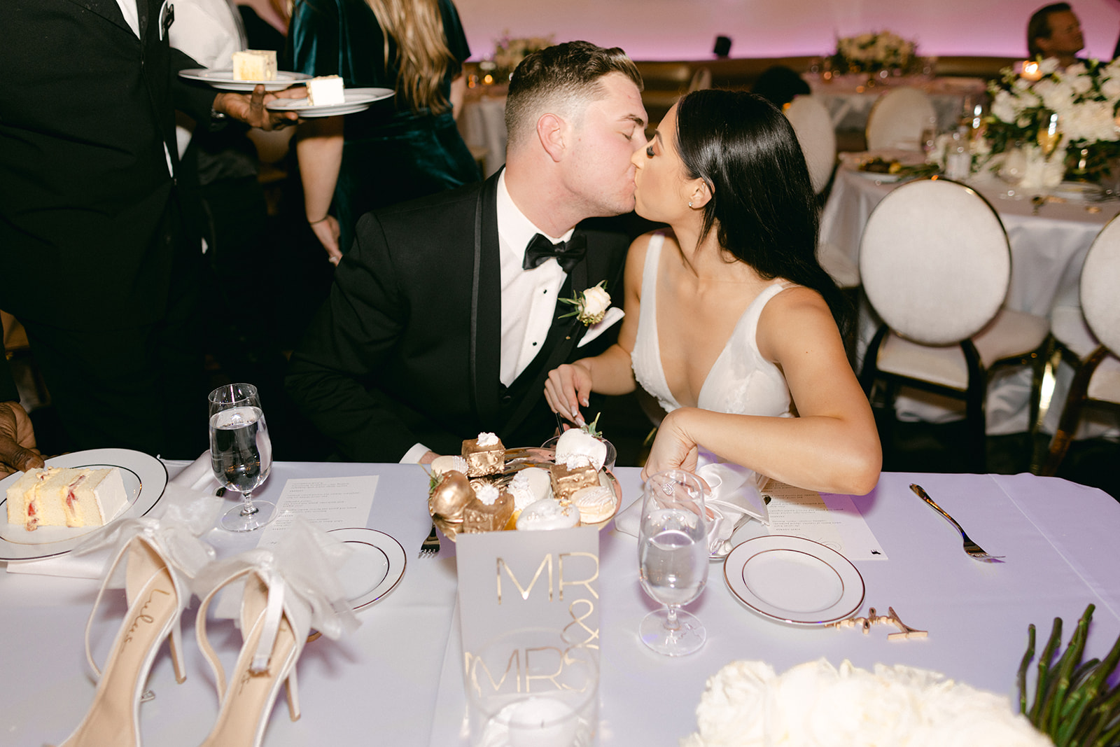 Bride and groom kissing at sweetheart table 