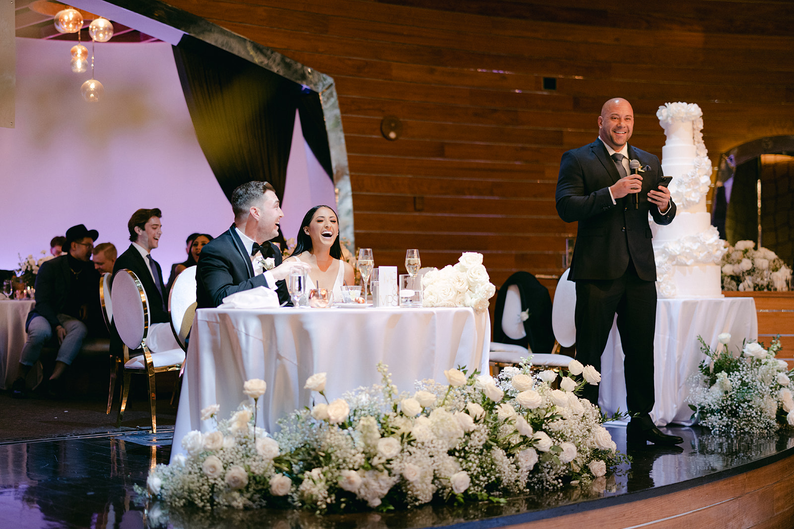 Newlyweds laughing during fathers speech 