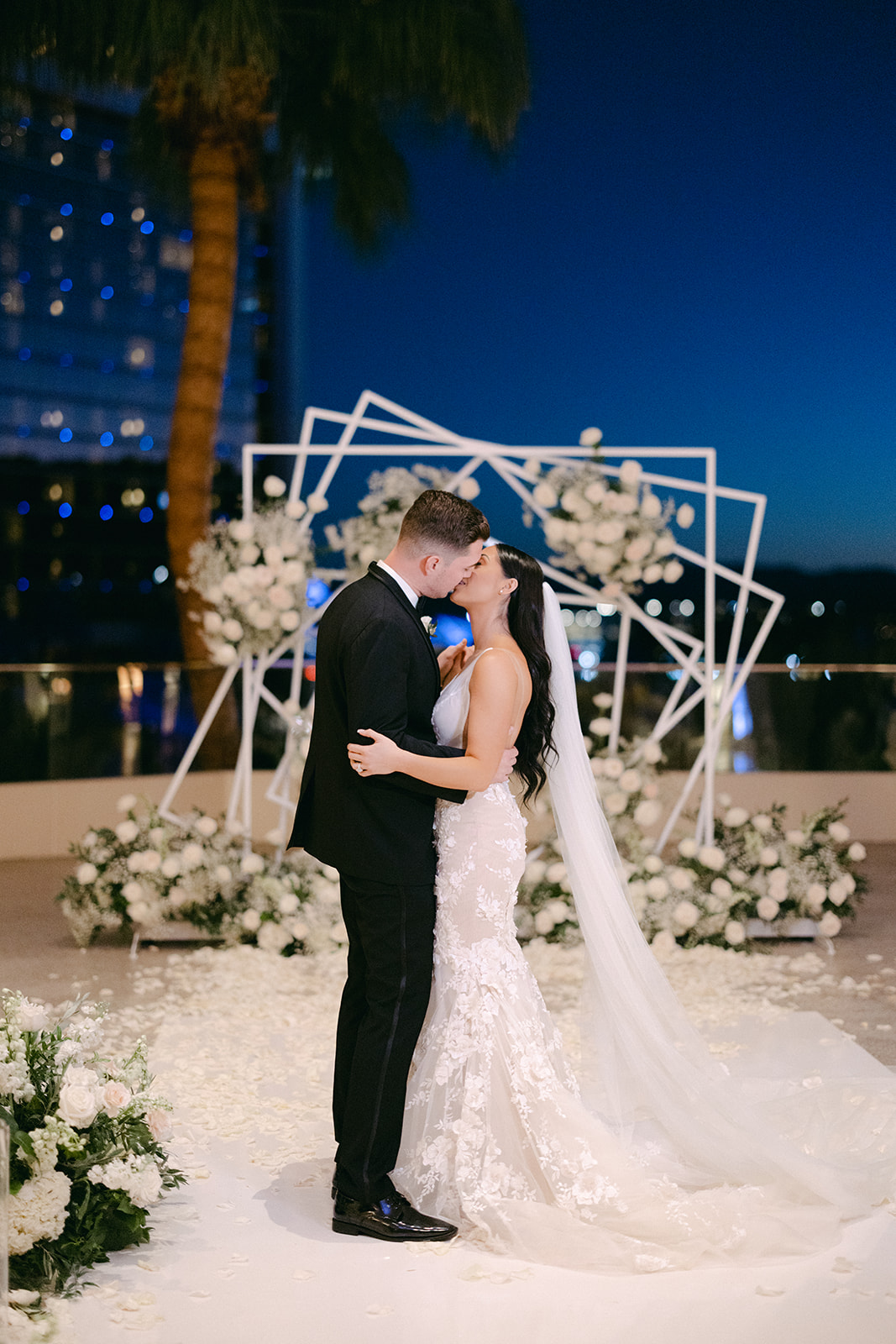 Bride and groom kissing in front of arch for Red Rock Casino Timeless Modern Wedding 