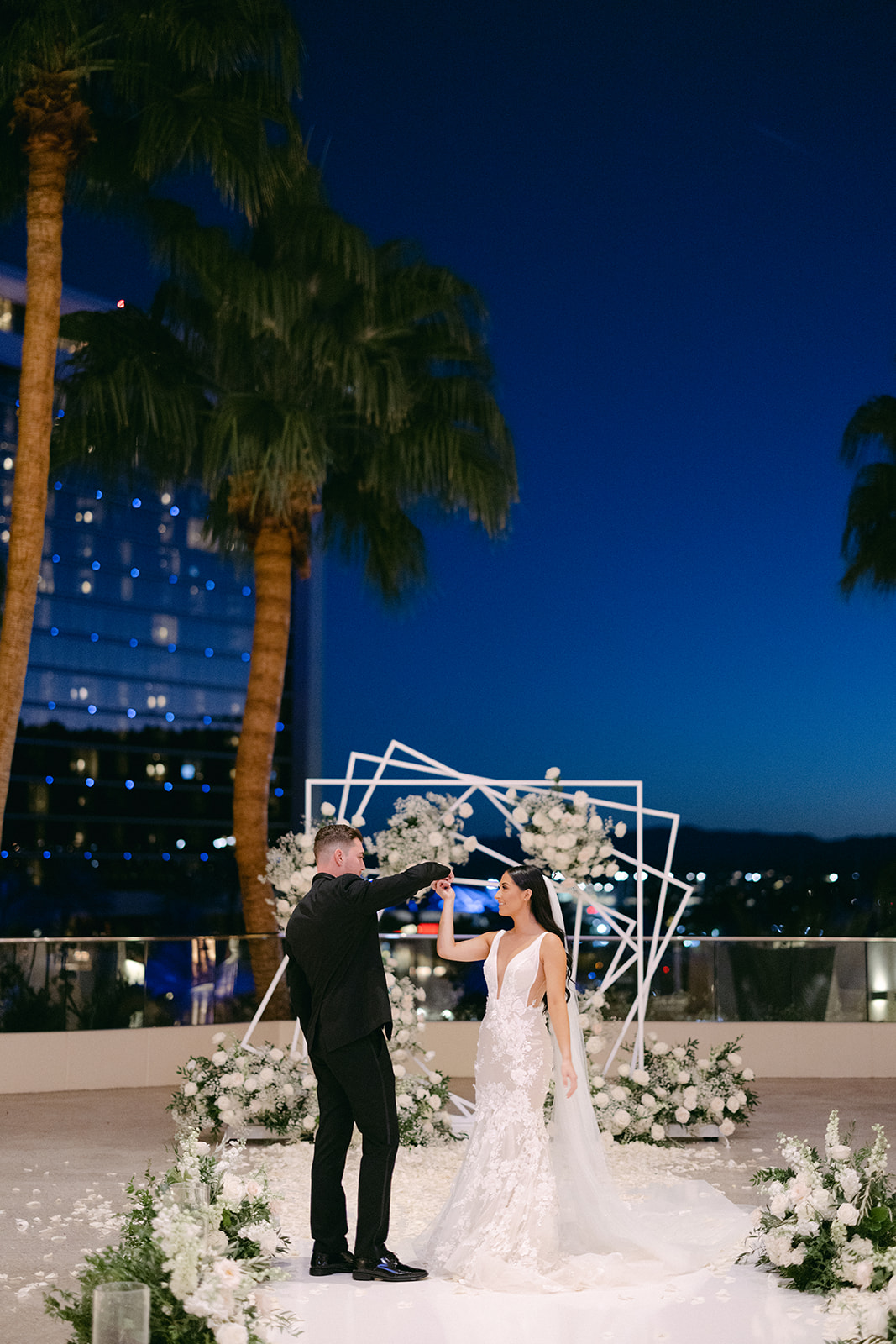 Bride and groom dancing in front of ceremony arch after getting married 