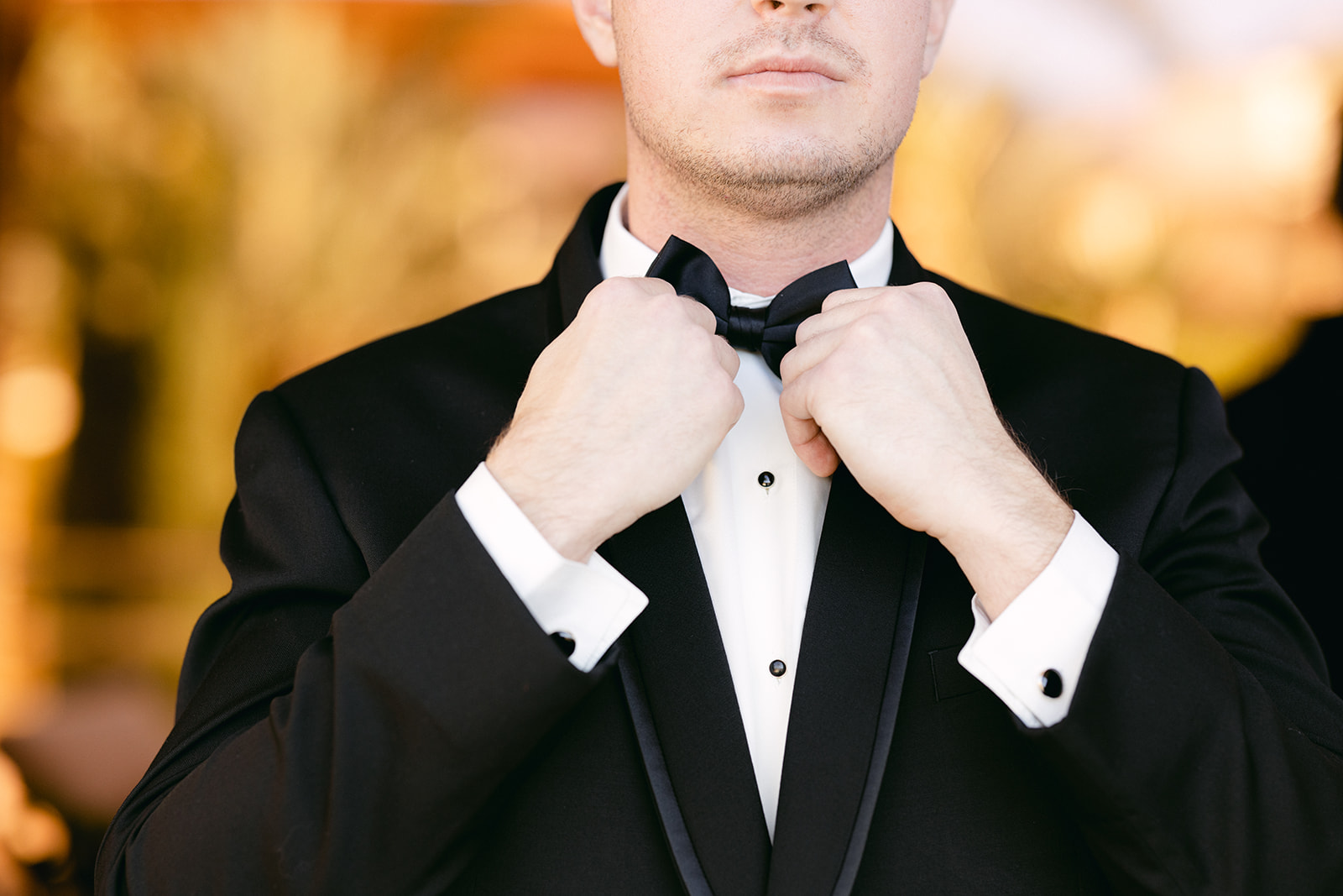 Groom in Tuxedo adjusting bow tie 