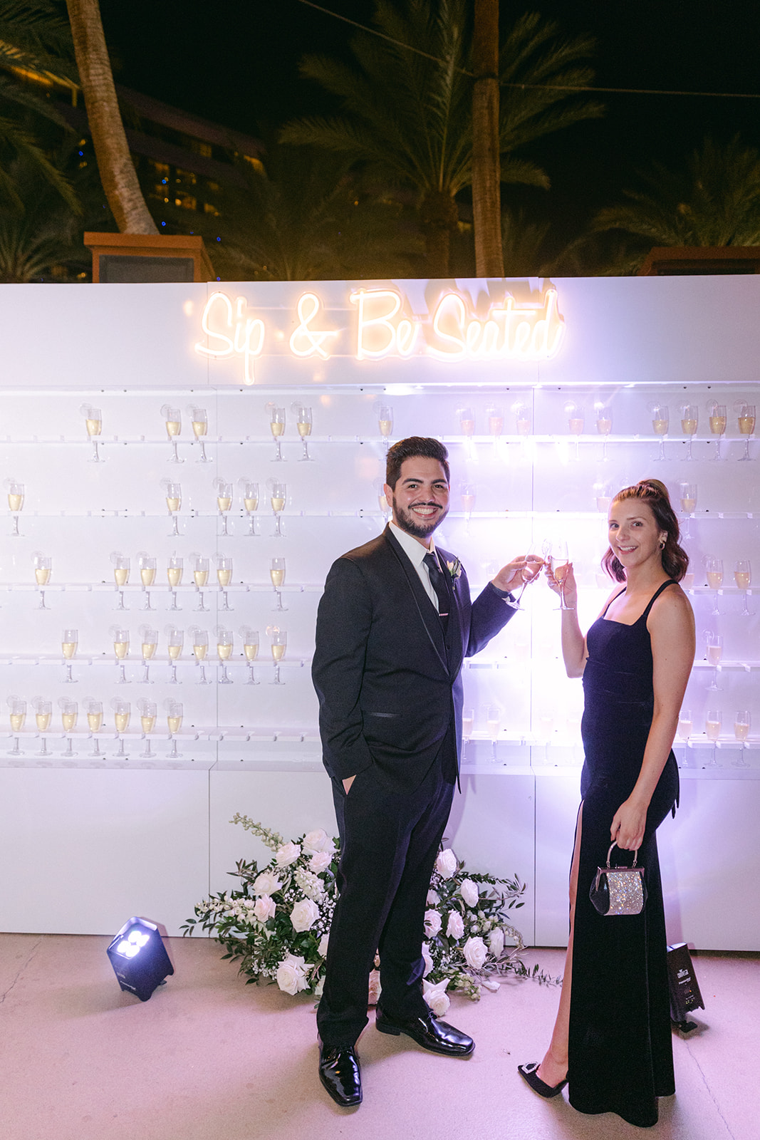 Guests in front of Champagne wall and Sip and Be Seated sign 