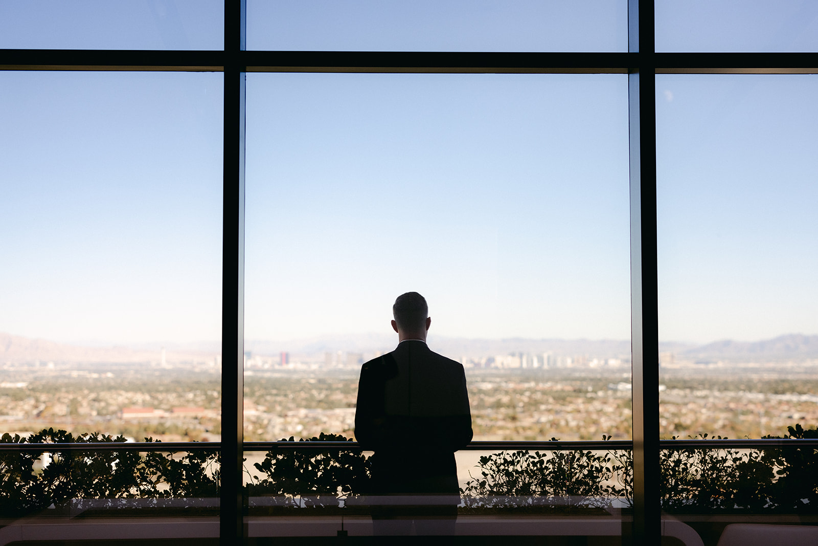 Groom looking out to Las Vegas view awaiting first look with bride for Red Rock Casino Timeless Modern Wedding 