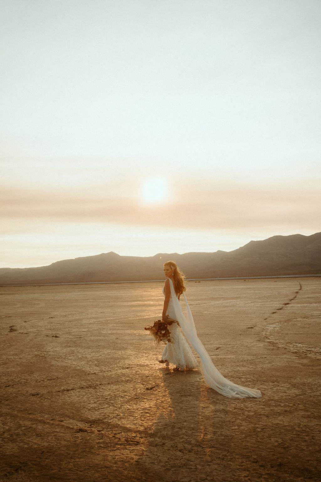Bride in Bridal Cape with Bouquet at Dry Lake Bed during Sunset 