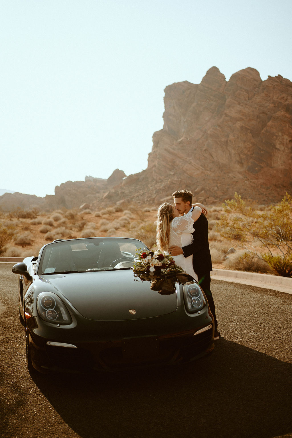 Bride & Groom Leaning on Porsche during Rolling out in Style in the Desert Elopement 