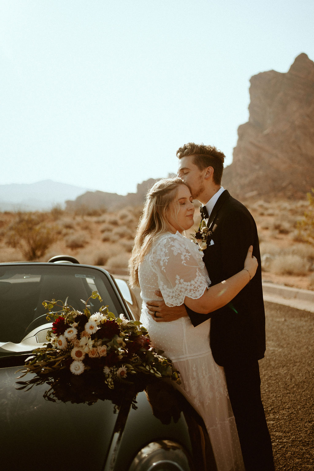 Groom Kissing Bride while Leaning on Porsche in Valley of Fire 