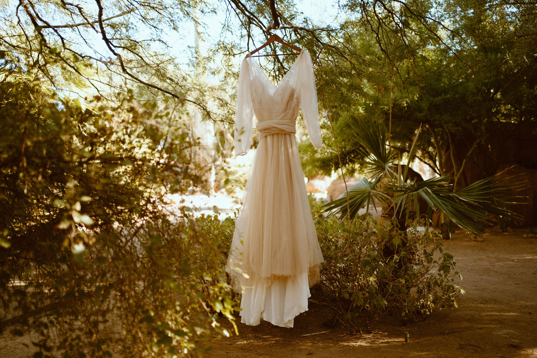 The brides beautiful wedding dress hanging in the garden 