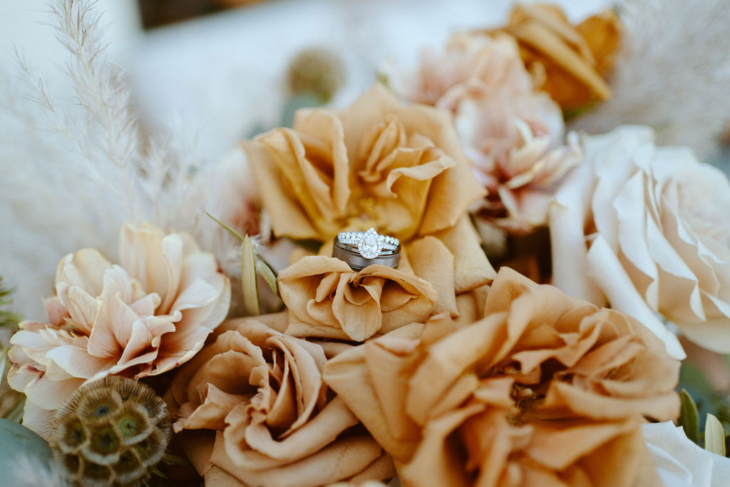 The bride and grooms wedding rings tucked into toffee colored roses
