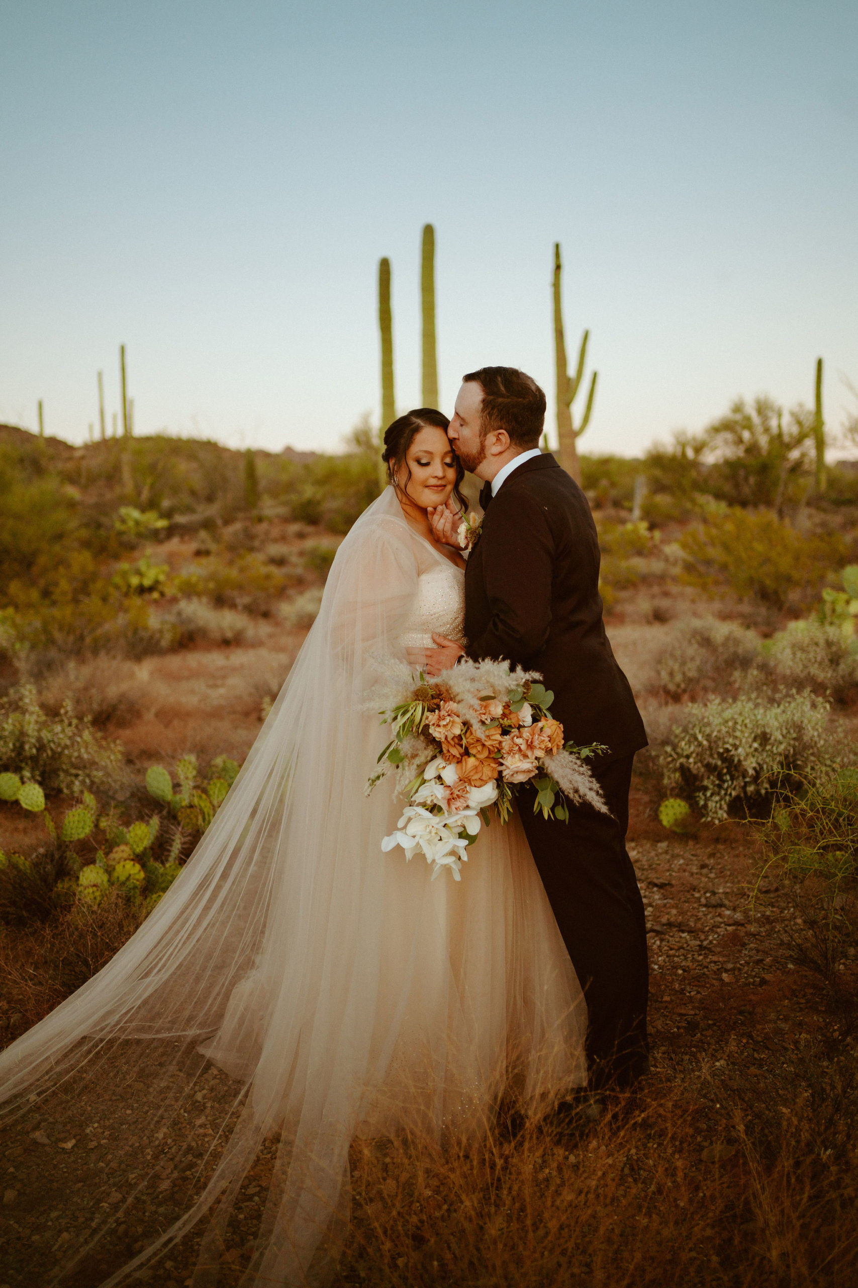 Saguaro National Park Micro-Wedding. The groom kissing the brides forehead as she leans in
