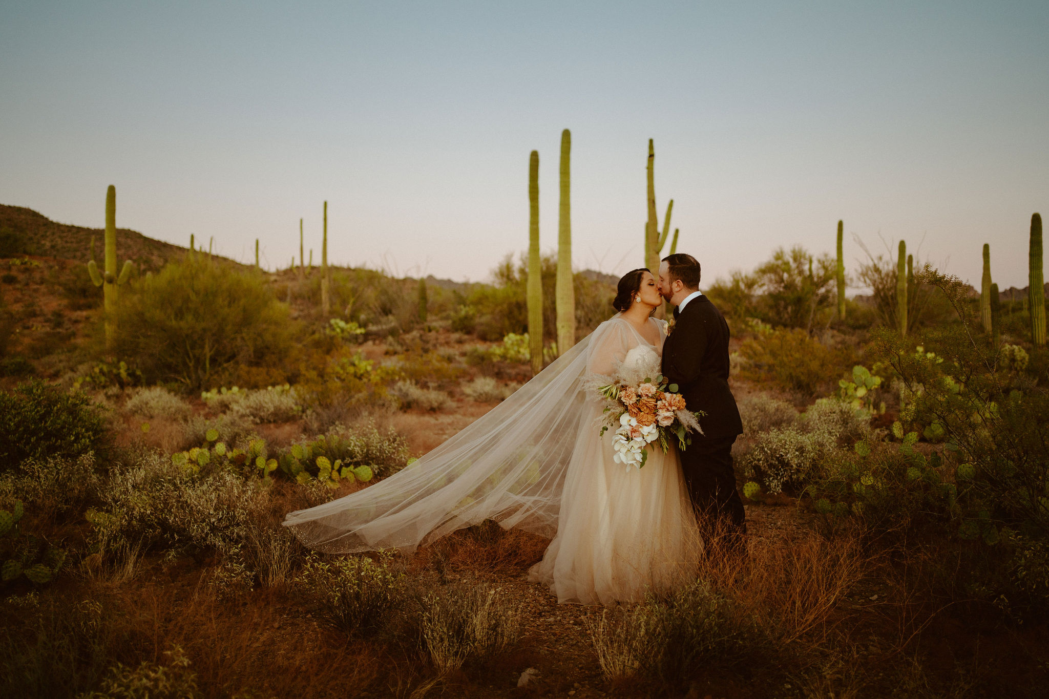 Saguaro National Park Micro-Wedding. Newlyweds kissing in the middle of the desert during sunset.