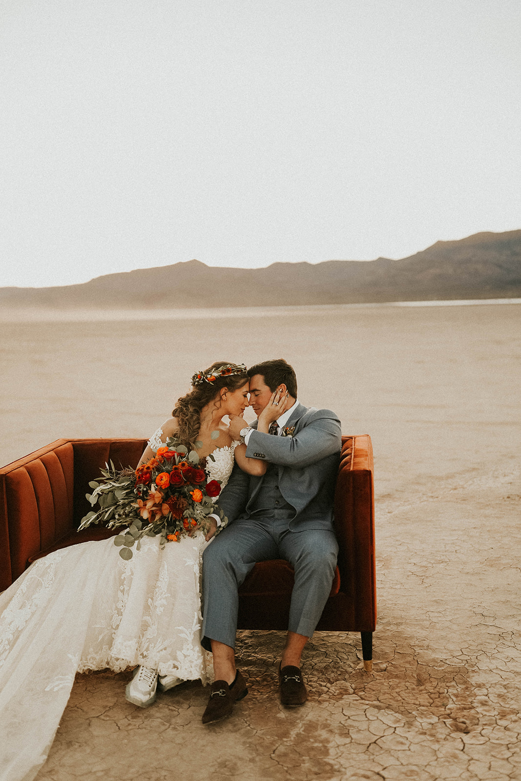 Newlyweds having a moment on Terra-cotta Velvet Couch in Desert as Wedding Photo Prop 