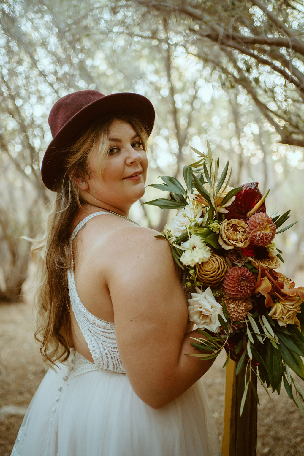 Bride in Hat holding Bouquet in Olive Grove 