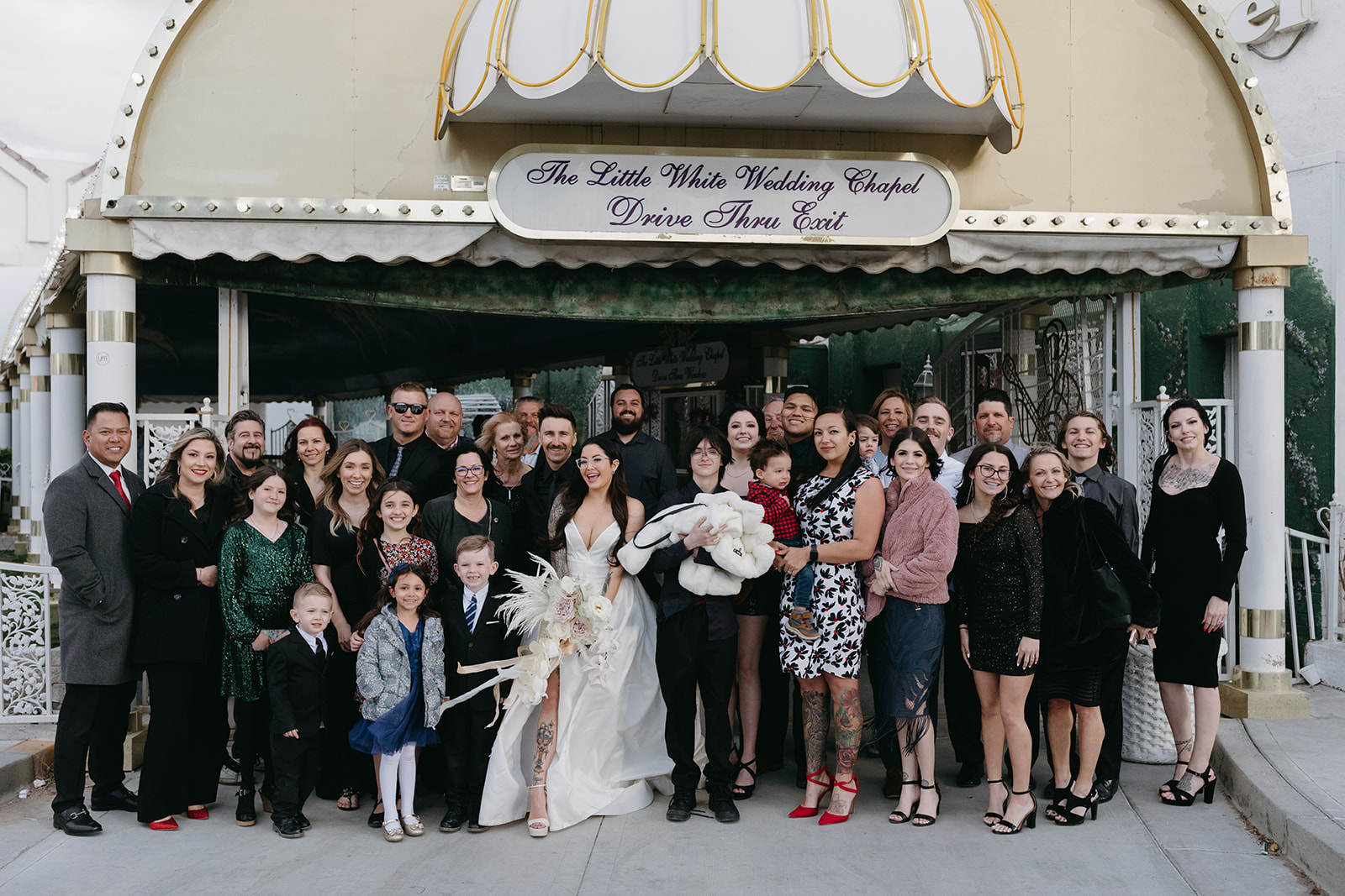 Group of Wedding Guests and Newlyweds outside A Little White Wedding Chapel after Ceremony 