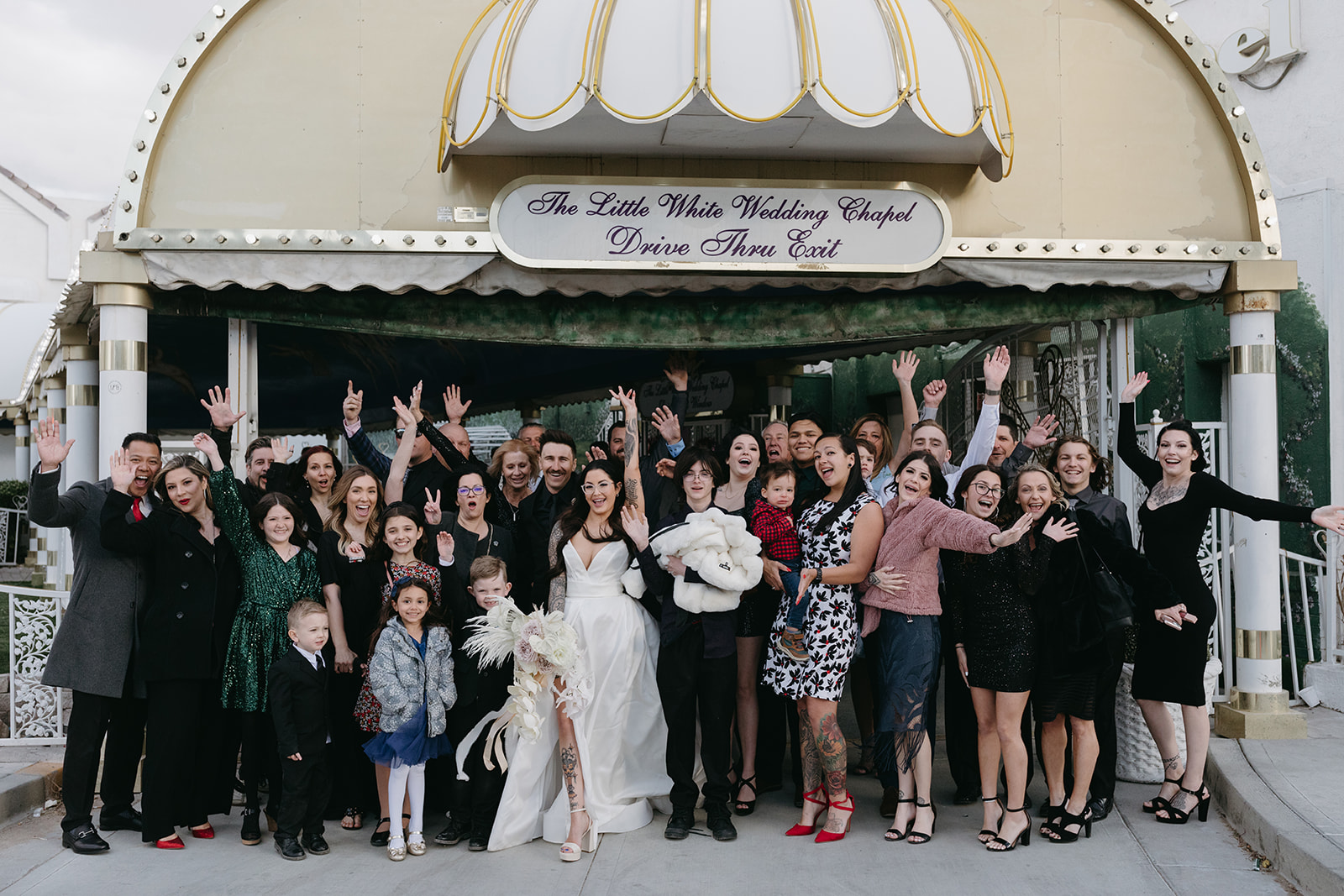 Group of Wedding Guests and Newlyweds Cheering outside A Little White Wedding Chapel after Ceremony 