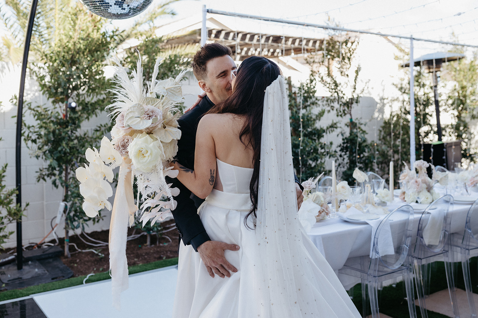 Couple Kissing after First Look while Bride is holding Neutral Colored Floral Bouquet with White Orchids