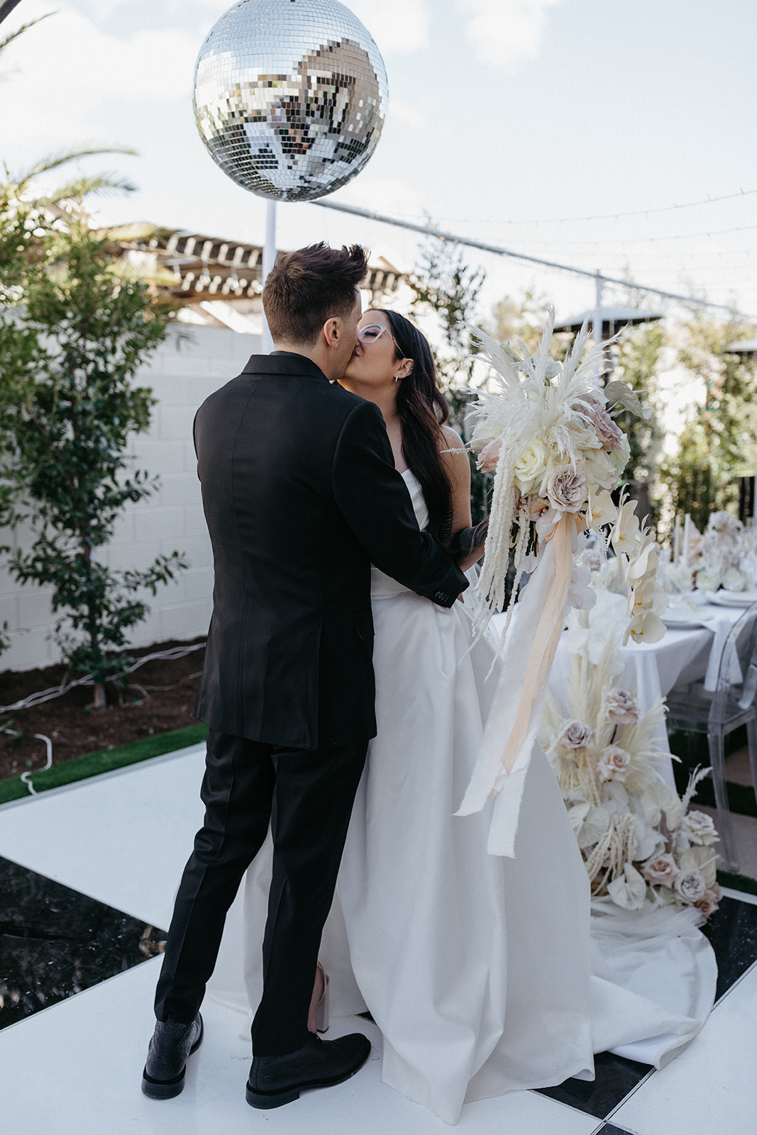 Couple Kissing under Disco Ball in Las Vegas Wedding with Modern Romantic Neutral Florals with White Orchids