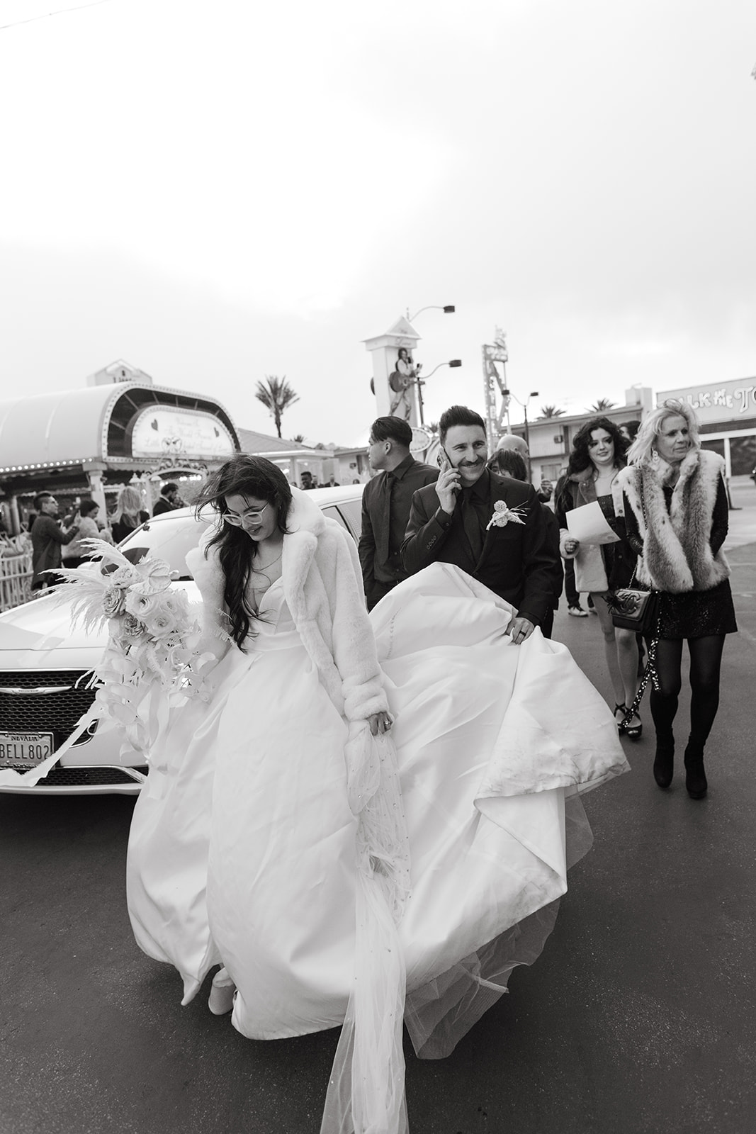 Black and White Photo of Bride and Groom Leaving Vegas Ceremony with Guests Following Behind 
