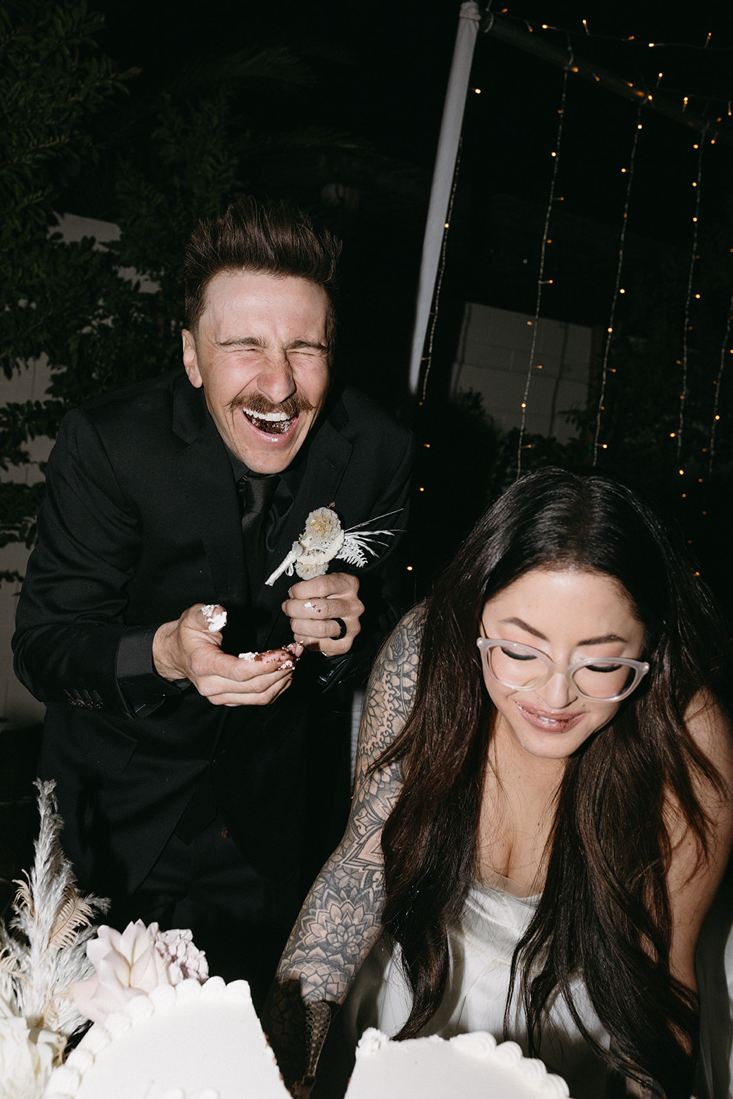 Newlyweds laughing while eating cake during Little White Wedding Chapel Modern Vegas Wedding