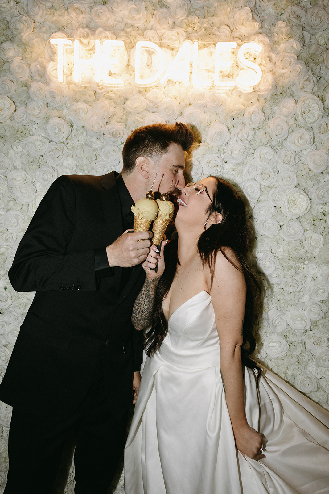 Bride and Groom with Gold Cherry Topped  Ice Cream Cones in Front of Flower Wall 