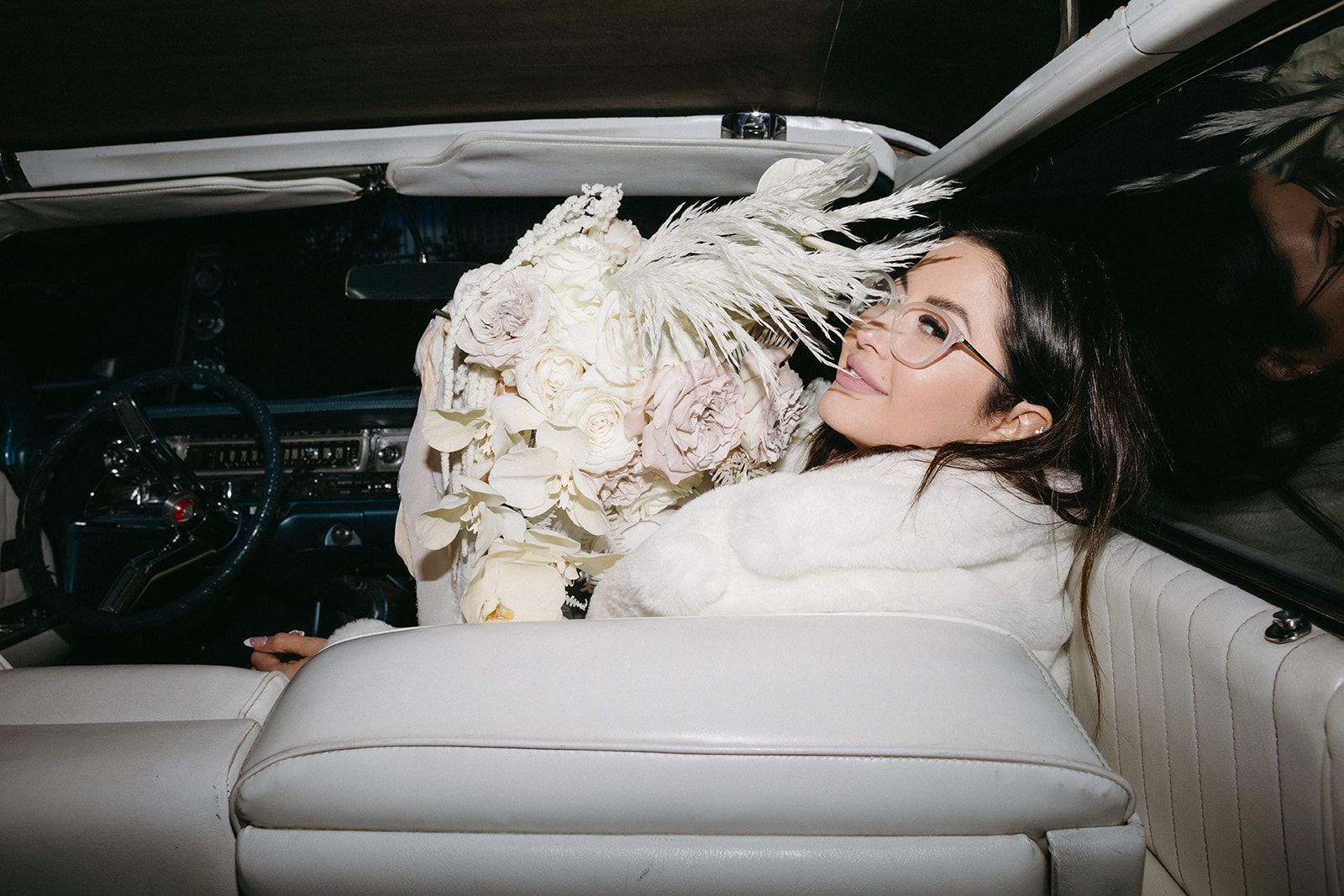 Bride in Classic Car and White Fur Coat holding White Monochromatic Bouquet 